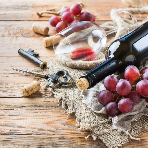 Бутылка, штопор, бокал красного вина, виноград на столе — стоковое фото