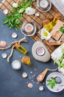 Spa natürmort sağlık ayarı kavramı. Uçucu yağ krem deniz tuzu doğal sabun mumlar ürün yelpazesine beyaz bahar çiçekleri ve havlu siyah bir tablo. Üstten Görünüm, düz yatıyordu
