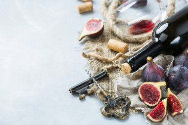 Şişe, tirbuşon, bardak kırmızı şarap, bir tabloda incir