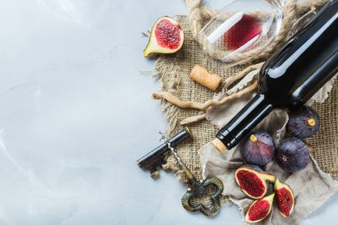 Şişe, tirbuşon, bardak kırmızı şarap, bir tabloda incir