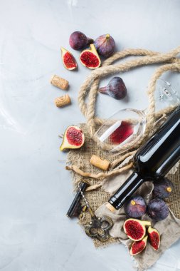 Şişe, tirbuşon, bardak kırmızı şarap, bir tabloda incir