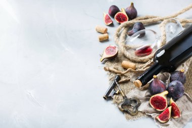 Şişe, tirbuşon, bardak kırmızı şarap, bir tabloda incir