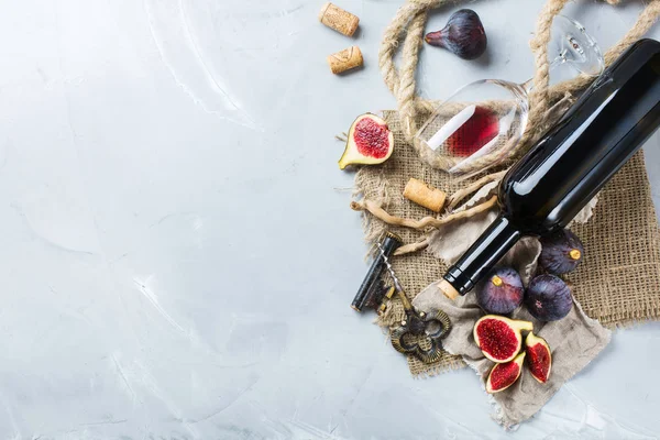 Fles, kurkentrekker, glas rode wijn, vijgen op een tafel — Stockfoto