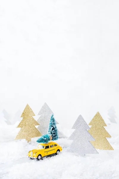 Toy car carrying christmas tree in a snow forest — Stock Photo, Image