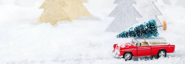 Carro de brinquedo carregando árvore de Natal em uma floresta de neve — Fotografia de Stock