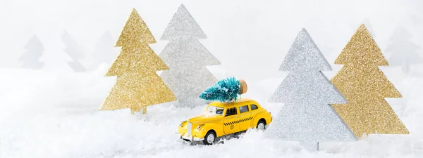 Toy car carrying christmas tree in a snow forest — Stock Photo, Image