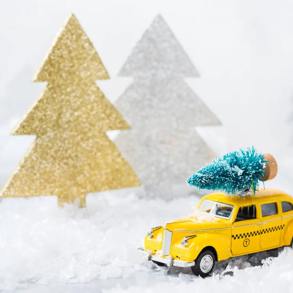 Toy car carrying christmas tree in a snow forest — Stock Photo, Image