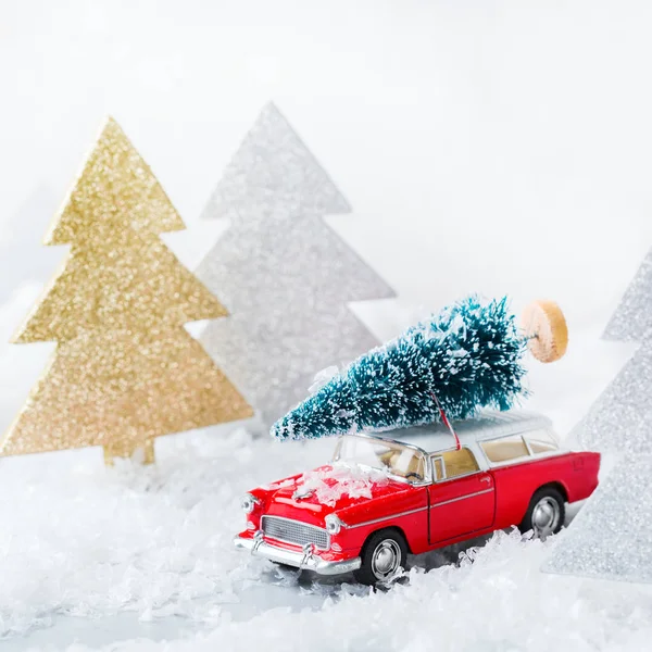 Toy car carrying christmas tree in a snow forest — Stock Photo, Image