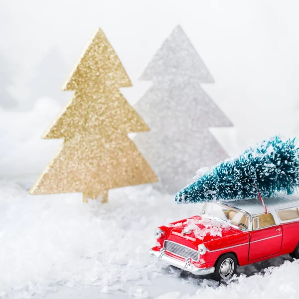 Toy car carrying christmas tree in a snow forest — Stock Photo, Image