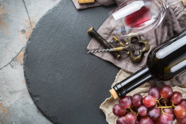 Şişe, tirbuşon, bardak kırmızı şarap, üzüm bir tablo