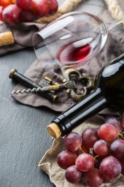 Şişe, tirbuşon, bardak kırmızı şarap, üzüm bir tablo