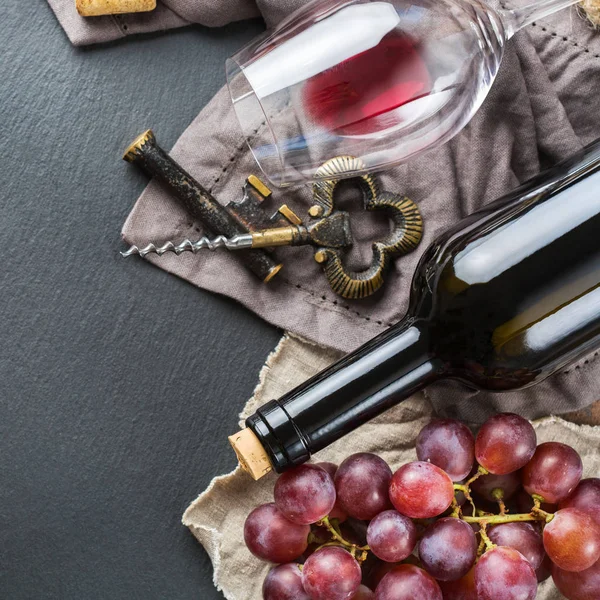 Şişe, tirbuşon, bardak kırmızı şarap, üzüm bir tablo