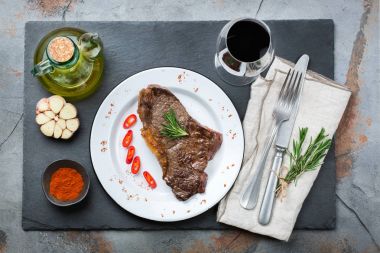 Yiyecek ve içecek konsepti. Sığır eti biftek ile baharat hazır karanlık tablo arka plan akşam yemeği için ızgara. Düz yatıyordu Üstten Görünüm