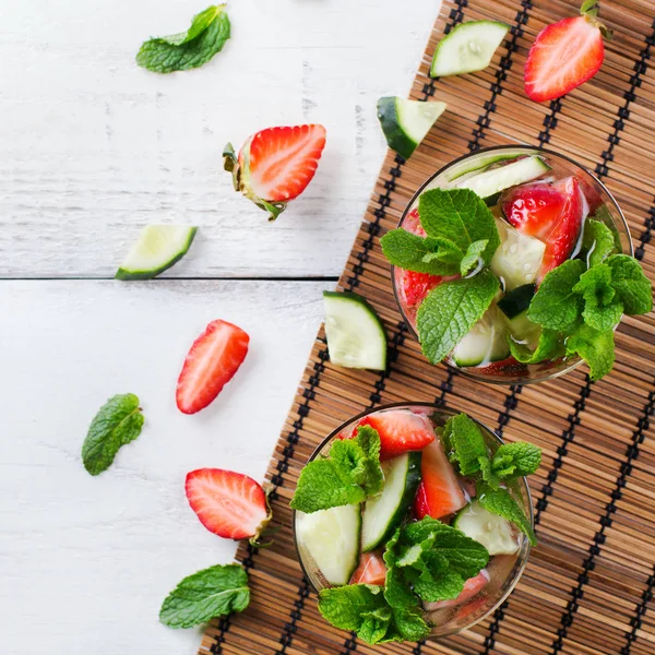 Healthcare, fitness, healthy nutrition concept. Fresh cool cucumber strawberry mint infused water, cocktail, detox drink, lemonade for spring summer days. Top view flat lay