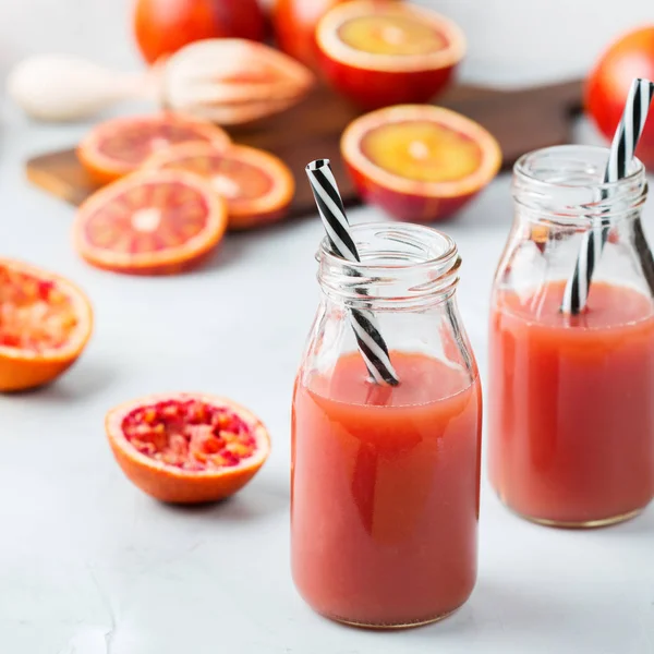 Yiyecek ve içecek, sağlık, diyet ve beslenme kavramı. Olgun organik narenciye bir şişe mutfak masası günü kahvaltıda taze kırmızı kan portakal suyu. Bahar Yaz içecek