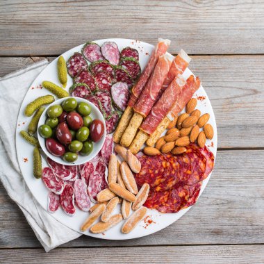 Natürmort, gıda ve içecek, tatil kavramı. İspanyolca tapas veya İtalyan antipasti et, salam, zeytin, peynir, fındık ve bir masada ekmek. Üst görüntülemek düz yatıyordu arka plan