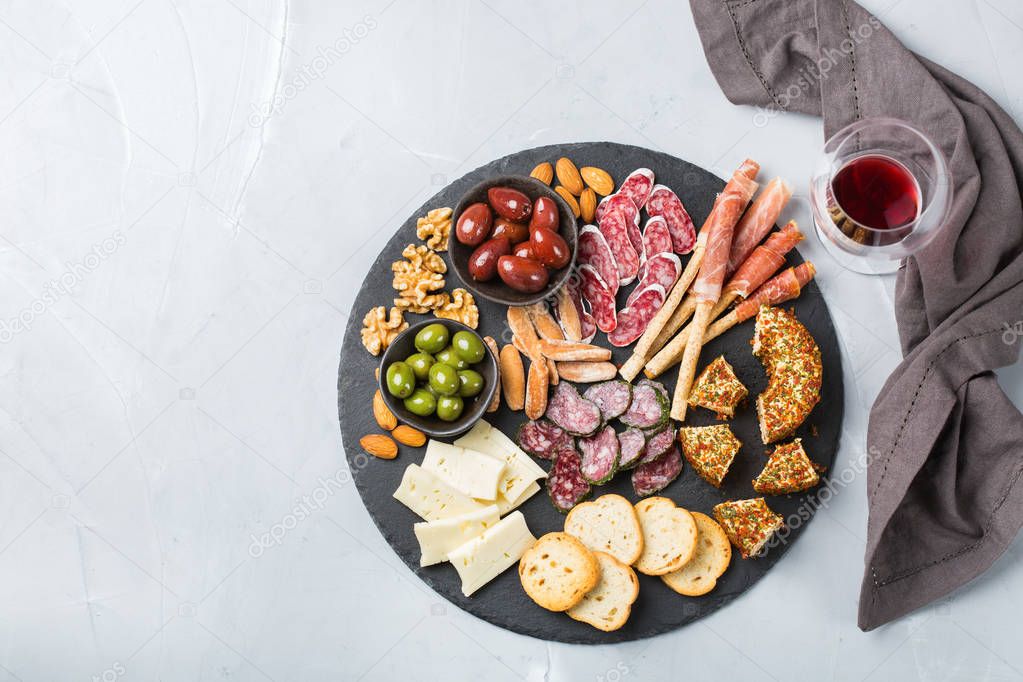 Still life, food and drink, holidays concept. Assortment of spanish tapas or italian antipasti with meat, ham, olives, cheese, nuts bread and wine on a table. Top view flat lay background