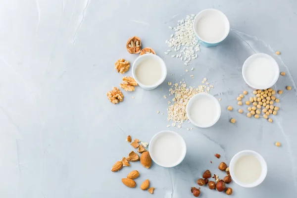 Food and drink, health care, diet and nutrition concept. Assortment of organic vegan non diary milk from nuts, oatmeal, rice, soy in glasses on a kitchen table. Copy space top view flat lay background