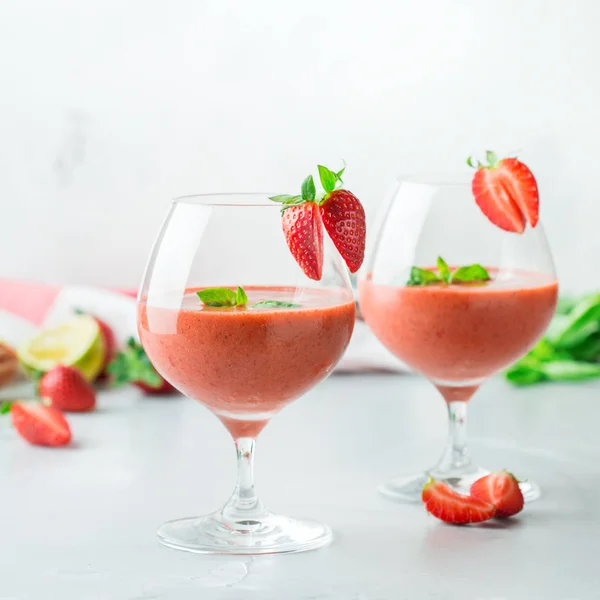 Food and drink, holidays party concept. Cold fresh alcohol beverage cocktail with vodka, lime, red strawberry, green basil and ice for refreshment in summer days
