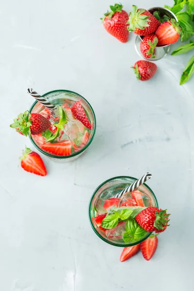 Food and drink, holidays party concept. Cold fresh alcohol beverage mojito cocktail in glasses with white rum, soda, red strawberry and basil for refreshment in summer days. Top view background