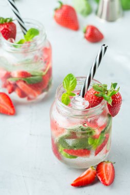 Gıda ve içecek, tatil partisi konsepti. Soğuk taze alkol içecek mojito beyaz rom, soda, kırmızı çilek ve yaz günlerinde serinlemek için fesleğen ile kokteyl