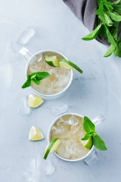 Food and drink, holidays party concept. Cold fresh classic alcohol beverage moscow mule cocktail in a silver mug with vodka, ginger beer. lime and mint for refreshment in summer days Top view flat lay