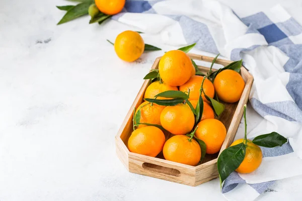 Свежие оранжевые мандарины, мандарины с зелеными листьями на столе — стоковое фото