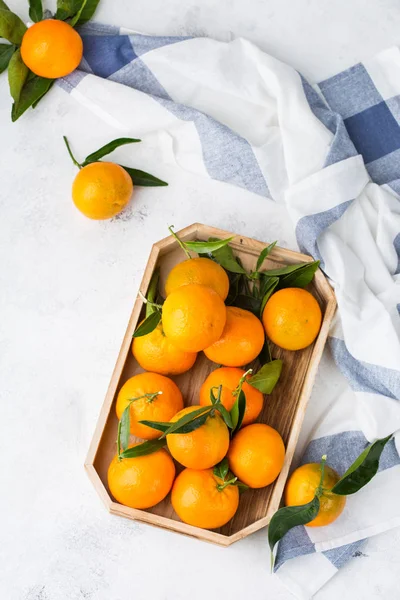 Verse sinaasappelmandarijnen, mandarijnen met groene bladeren op een tafel — Stockfoto