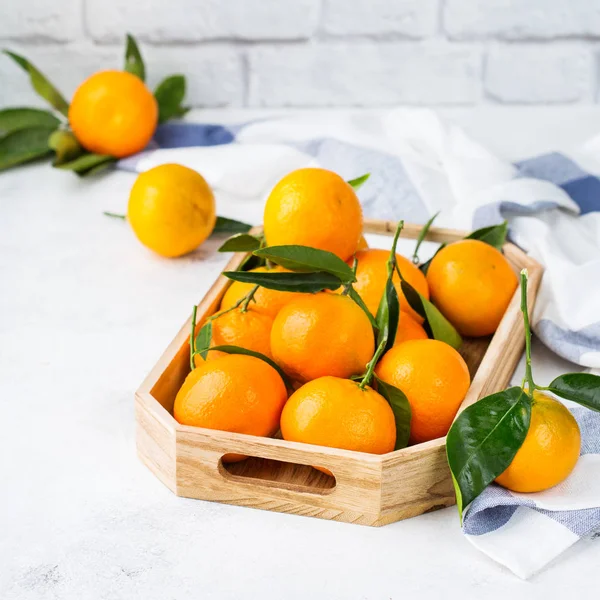 Свежие оранжевые мандарины, мандарины с зелеными листьями на столе — стоковое фото