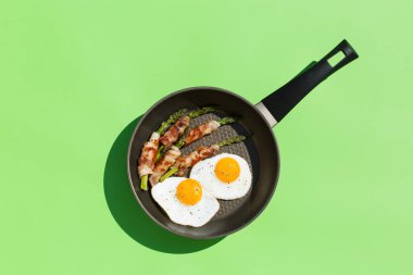 Dengeli beslenme keto besin konsepti. Sağlıklı ketojenik düşük karbonhidratlı yumurta, pastırma, tavada kuşkonmaz. Moda güneşli, canlı, sert ve sert ışık ve yeşil arkaplanda gölgeler