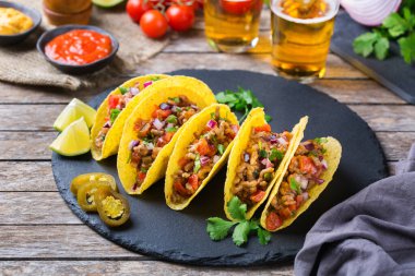 Taco kabuğu, mısır cipsi kıyma, kıyma, guacamole, kırmızı acı biber sosu ve peynir soslu tekila ya da birayla kaplı cips cipsi..