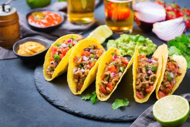 Taco kabuğu, mısır cipsi kıyma, kıyma, guacamole, kırmızı acı biber sosu ve peynir soslu tekila ya da birayla kaplı cips cipsi..