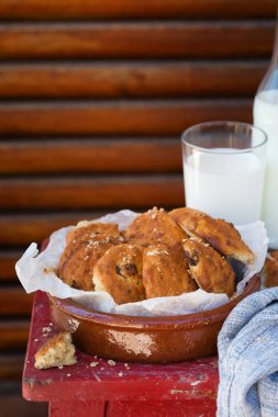 Kuru üzümlü ev yapımı yulaflı kurabiyeler ve eski bir ahşap zeminde bir bardak süt..