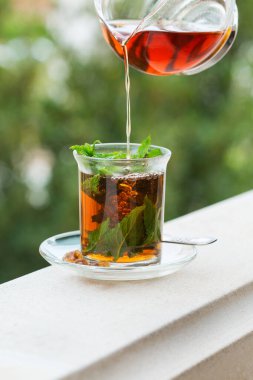 Stres, anksiyete, kronik yorgunluk, depresyon ve rahatlama için iç. Bir bardak kamış şekerli sıcak nane çayı, geleneksel Orta Doğu, Fas, Arap, kırsal içeceği çaydanlıktan dökülüyor.