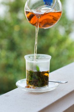 Stres, anksiyete, kronik yorgunluk, depresyon ve rahatlama için iç. Bir bardak kamış şekerli sıcak nane çayı, geleneksel Orta Doğu, Fas, Arap, kırsal içeceği çaydanlıktan dökülüyor.