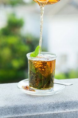Stres, anksiyete, kronik yorgunluk, depresyon ve rahatlama için iç. Bir bardak kamış şekerli sıcak nane çayı, geleneksel Orta Doğu, Fas, Arap, kırsal içeceği çaydanlıktan dökülüyor.