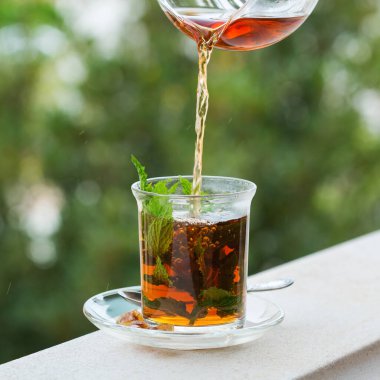 Stres, anksiyete, kronik yorgunluk, depresyon ve rahatlama için iç. Bir bardak kamış şekerli sıcak nane çayı, geleneksel Orta Doğu, Fas, Arap, kırsal içeceği çaydanlıktan dökülüyor.