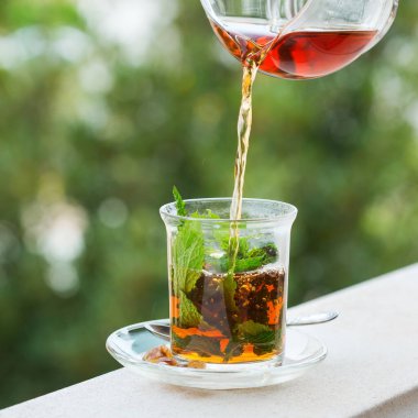 Stres, anksiyete, kronik yorgunluk, depresyon ve rahatlama için iç. Bir bardak kamış şekerli sıcak nane çayı, geleneksel Orta Doğu, Fas, Arap, kırsal içeceği çaydanlıktan dökülüyor.