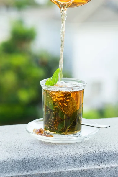 Stres, anksiyete, kronik yorgunluk, depresyon ve rahatlama için iç. Bir bardak kamış şekerli sıcak nane çayı, geleneksel Orta Doğu, Fas, Arap, kırsal içeceği çaydanlıktan dökülüyor.