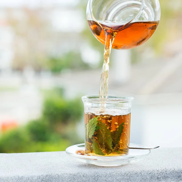 Stres, anksiyete, kronik yorgunluk, depresyon ve rahatlama için iç. Bir bardak kamış şekerli sıcak nane çayı, geleneksel Orta Doğu, Fas, Arap, kırsal içeceği çaydanlıktan dökülüyor.