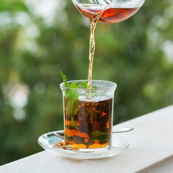 Stres, anksiyete, kronik yorgunluk, depresyon ve rahatlama için iç. Bir bardak kamış şekerli sıcak nane çayı, geleneksel Orta Doğu, Fas, Arap, kırsal içeceği çaydanlıktan dökülüyor.