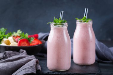 Yiyecek ve içecek, sağlıklı beslenme ve beslenme, yaşam tarzı, vegan, alkalin, vejetaryen konsepti. Modern bir mutfak masasında muzlu ve çilekli pembe smoothie. Boşluk arkaplanı kopyala