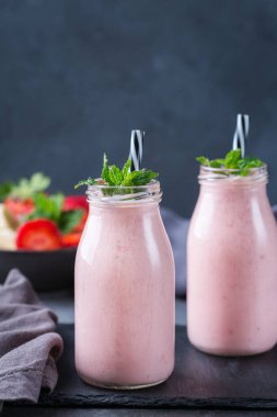 Yiyecek ve içecek, sağlıklı beslenme ve beslenme, yaşam tarzı, vegan, alkalin, vejetaryen konsepti. Modern bir mutfak masasında muzlu ve çilekli pembe smoothie. Boşluk arkaplanı kopyala