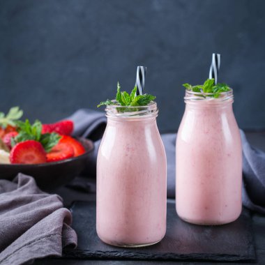 Yiyecek ve içecek, sağlıklı beslenme ve beslenme, yaşam tarzı, vegan, alkalin, vejetaryen konsepti. Modern bir mutfak masasında muzlu ve çilekli pembe smoothie. Boşluk arkaplanı kopyala