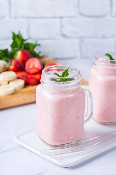 Food and drink, healthy dieting and nutrition, lifestyle, vegan, alkaline, vegetarian concept. Pink smoothie with banana and strawberry on a modern kitchen table. Copy space background