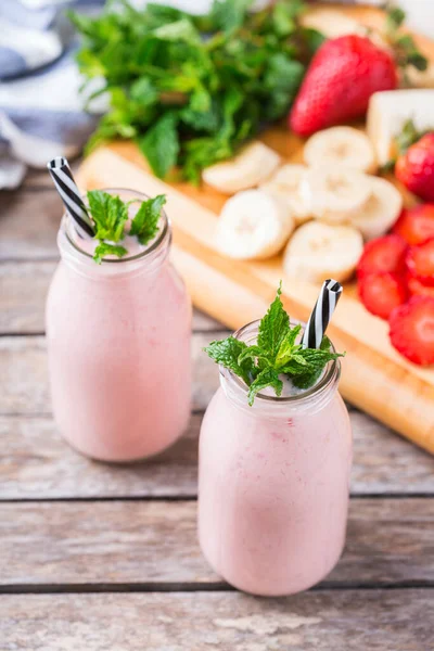 Food and drink, healthy dieting and nutrition, lifestyle, vegan, alkaline, vegetarian concept. Pink smoothie with banana and strawberry on a modern kitchen table. Copy space background
