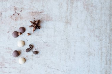 Baharatlar: Tarçın, karanfil, cips, kahve çekirdekleri, antika bir arka planda duran beyaz ve siyah çikolata damlaları.