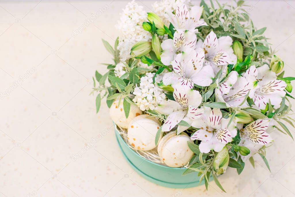 Blue gift box with beautiful flowers white alstroemeria and macarons on the white background.Florist at work.Gorgeous floral of arrangement,composition for birthday,wedding,happy moments.Copy space