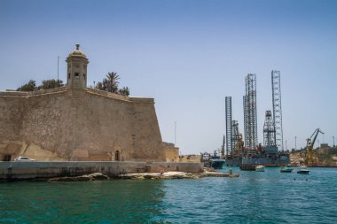 Deniz manzaralı Malta. Malta 'nın başkenti Valletta' nın geleneksel evleri ve duvarları açık mavi gökyüzüyle gün doğumundan önceki bir yaz sabahı. Üç Şehir Körfezi.
