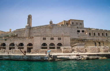 Deniz manzaralı Malta. Malta 'nın başkenti Valletta' nın geleneksel evleri ve duvarları açık mavi gökyüzüyle gün doğumundan önceki bir yaz sabahı. Üç Şehir Körfezi.